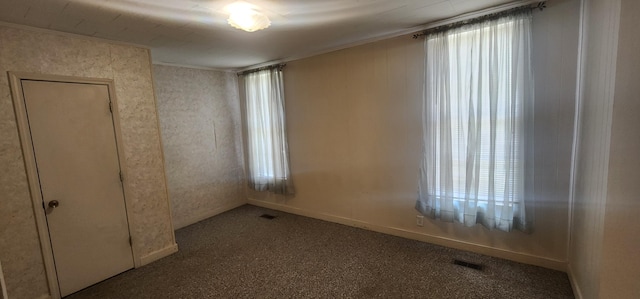 empty room featuring visible vents, a healthy amount of sunlight, carpet flooring, and crown molding