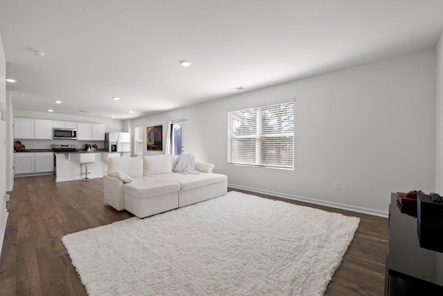 living area with visible vents, baseboards, dark wood finished floors, and recessed lighting