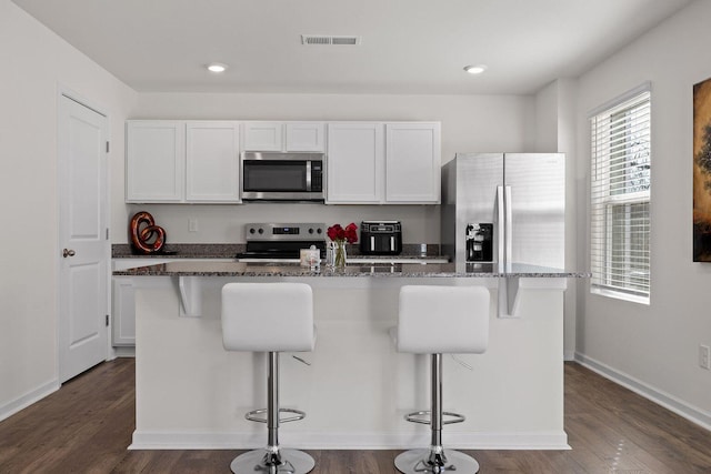 kitchen with dark wood-style floors, appliances with stainless steel finishes, visible vents, and white cabinets