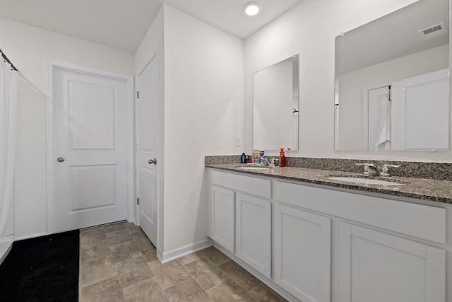 full bath with visible vents, a sink, baseboards, and double vanity