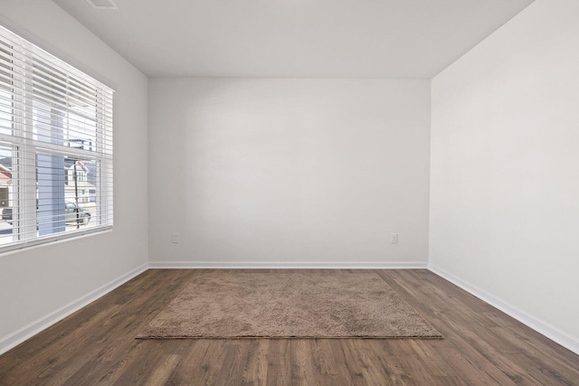 empty room featuring visible vents, baseboards, and wood finished floors