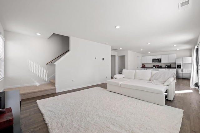 living room featuring recessed lighting, dark wood-style flooring, visible vents, baseboards, and stairway