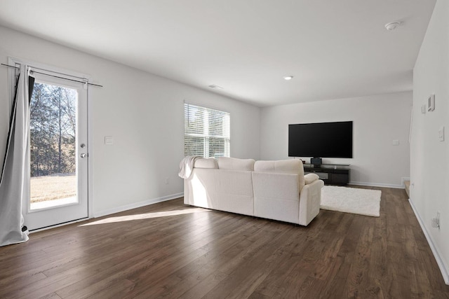 unfurnished living room with plenty of natural light, baseboards, and dark wood finished floors