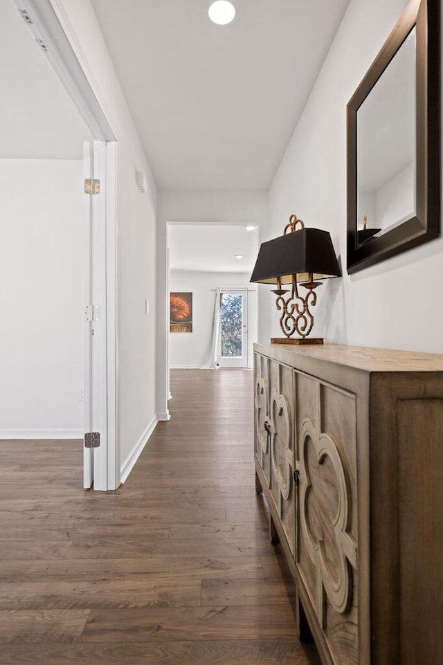 corridor with dark wood-type flooring and baseboards