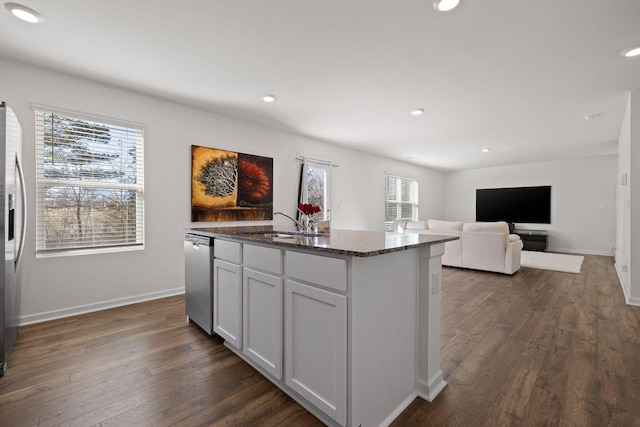 kitchen with dark stone counters, appliances with stainless steel finishes, plenty of natural light, and a sink