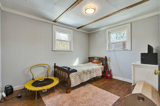 bedroom featuring dark hardwood / wood-style flooring, wooden walls, and multiple windows