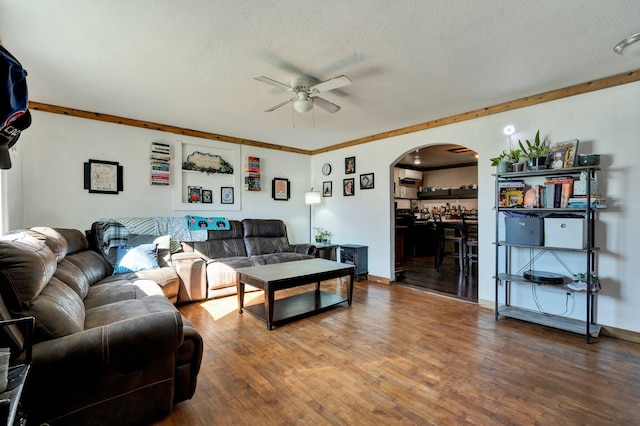 living room with a textured ceiling, hardwood / wood-style flooring, ceiling fan, and crown molding