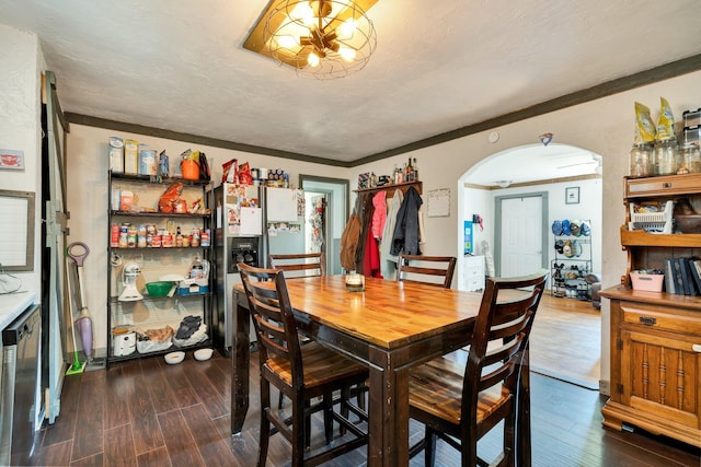 dining space featuring a textured ceiling, ornamental molding, and dark wood-type flooring