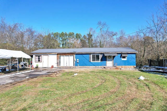 view of front of property with a carport, a front yard, and a trampoline