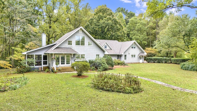 view of front facade with a front yard, a sunroom, and a chimney