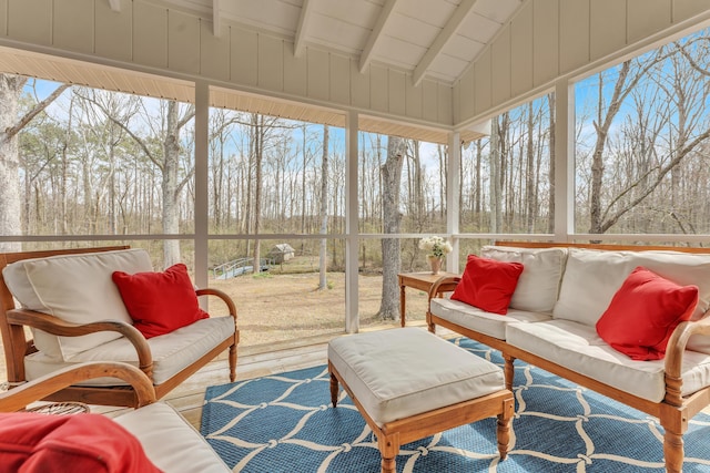 sunroom / solarium featuring vaulted ceiling with beams