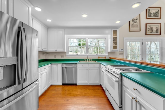 kitchen featuring a sink, appliances with stainless steel finishes, white cabinets, and light wood finished floors