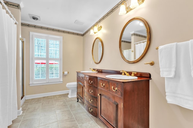 bathroom featuring toilet, a sink, crown molding, double vanity, and baseboards