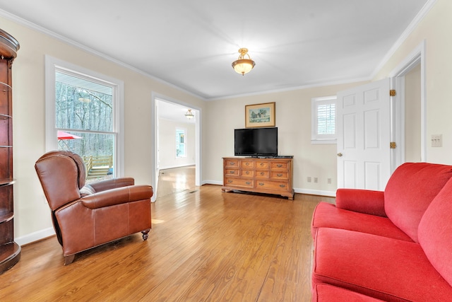 living area with light wood-style floors, baseboards, and ornamental molding