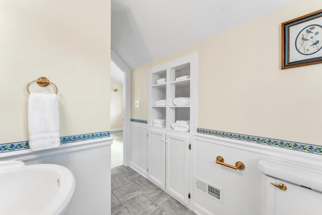 bathroom with a sink, visible vents, and wainscoting