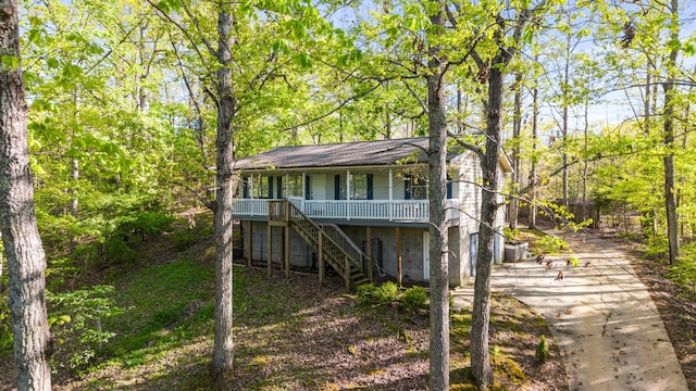 back of property featuring concrete driveway, stairs, and covered porch