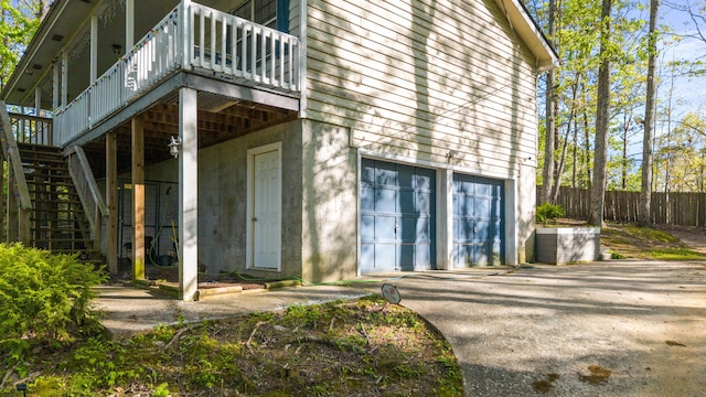 exterior space with a wooden deck, aphalt driveway, fence, and a garage