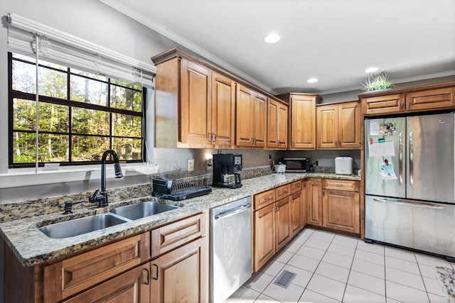 kitchen featuring stainless steel appliances, a sink, light stone counters, crown molding, and light tile patterned floors
