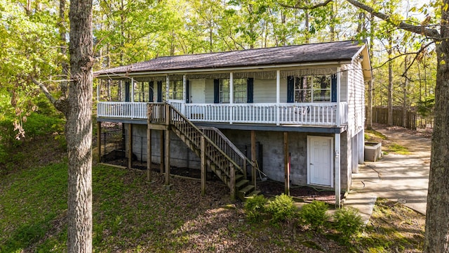 back of house featuring stairway, a porch, and driveway