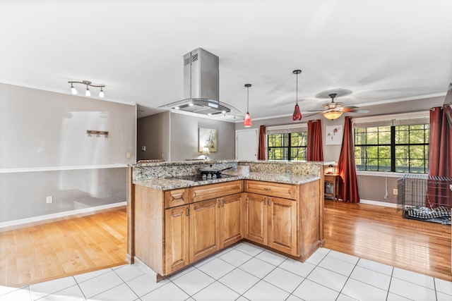 kitchen featuring island range hood, a ceiling fan, light wood-style floors, baseboards, and black electric stovetop