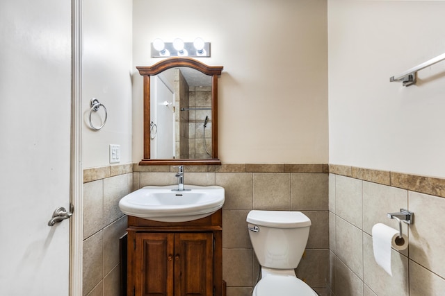 bathroom with wainscoting, toilet, vanity, and tile walls