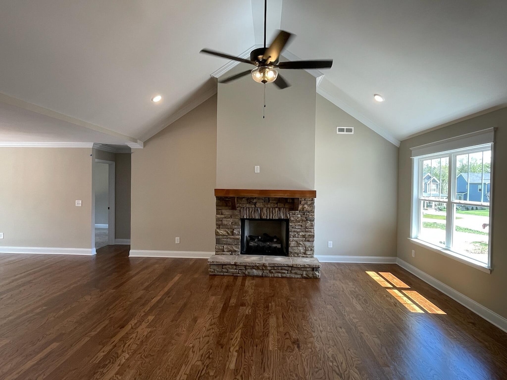 unfurnished living room with dark wood-type flooring, crown molding, vaulted ceiling, ceiling fan, and a fireplace