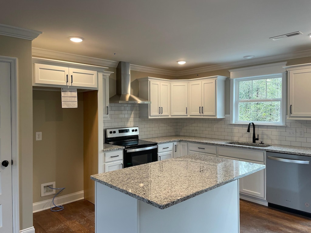 kitchen featuring white cabinets, appliances with stainless steel finishes, sink, and wall chimney range hood