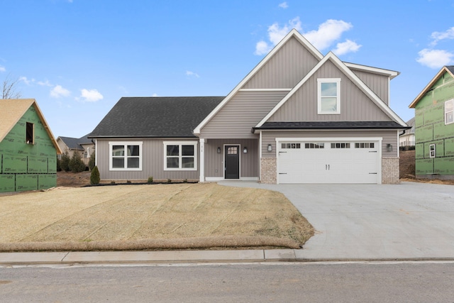 view of front of house featuring a garage, concrete driveway, brick siding, and roof with shingles