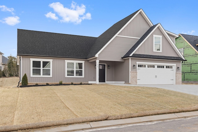 view of front of home featuring a shingled roof, concrete driveway, and brick siding