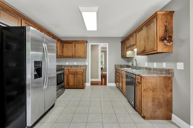 1010 Bradford Pl, Cohutta, GA 30710 - kitchen featuring appliances with stainless steel finishes, brown cabinetry, a sink, baseboards, and light tile patterned floors