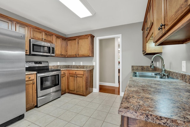 1010 Bradford Pl, Cohutta, GA 30710 - kitchen with stainless steel appliances, a sink, brown cabinetry, light tile patterned flooring, and baseboards