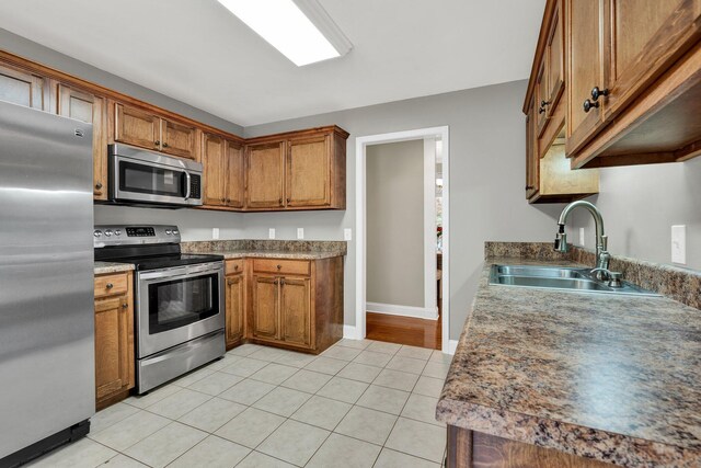 1010 Bradford Pl, Cohutta, GA 30710 - kitchen with stainless steel appliances, a sink, brown cabinetry, light tile patterned flooring, and baseboards