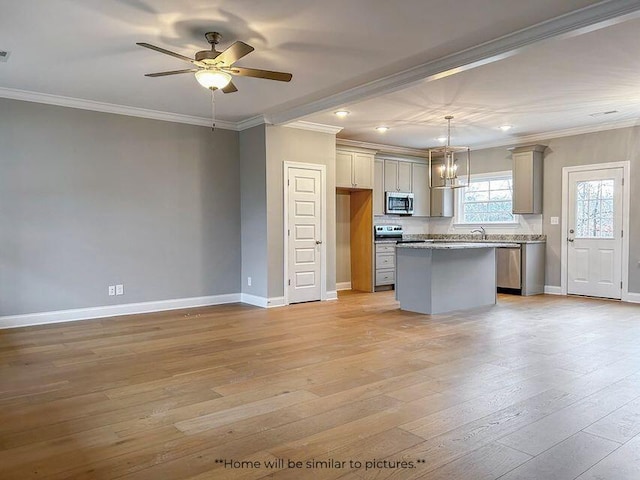 kitchen with appliances with stainless steel finishes, a kitchen island, light wood-style floors, and crown molding