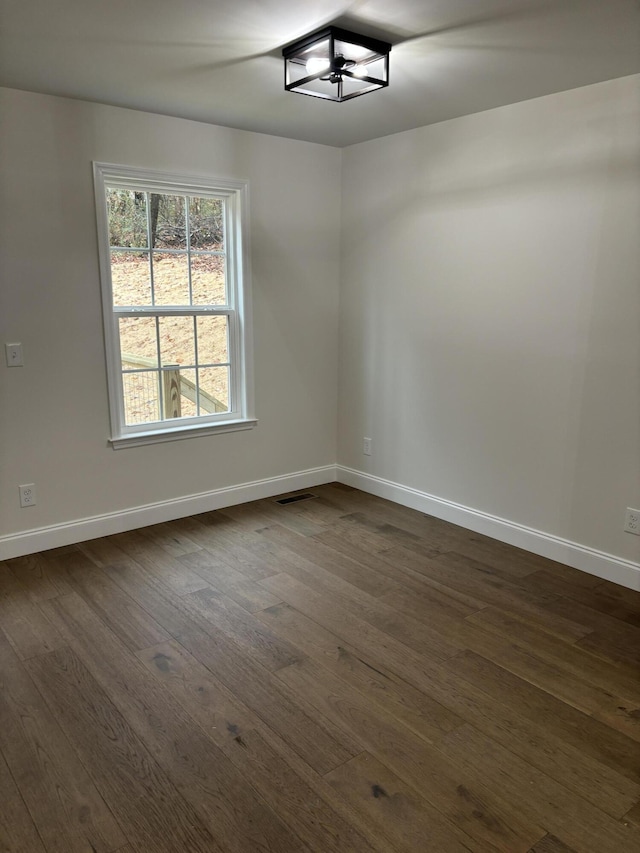 unfurnished room with dark wood-type flooring and an inviting chandelier