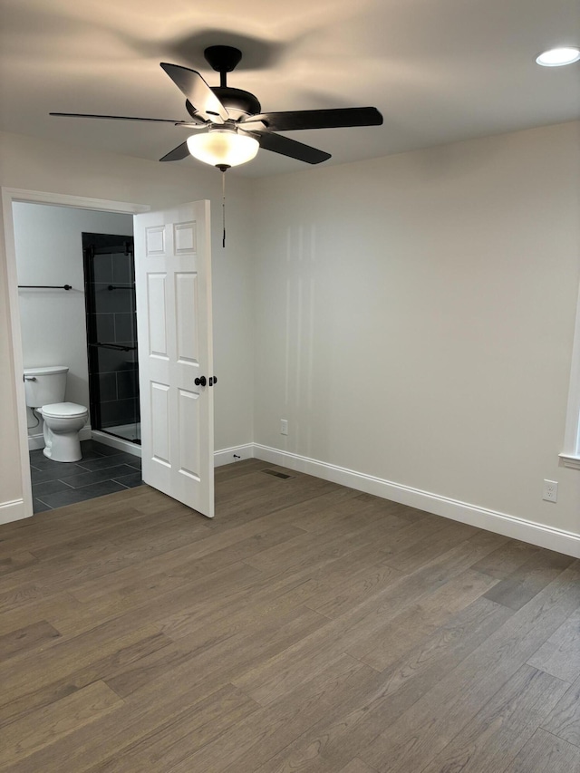 unfurnished bedroom featuring ceiling fan, dark hardwood / wood-style flooring, and connected bathroom