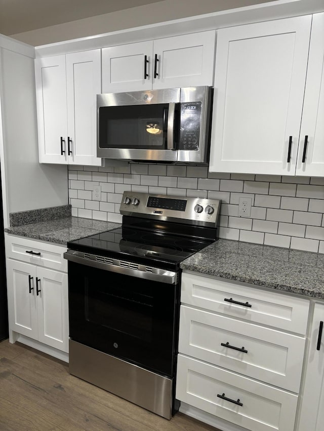 kitchen featuring white cabinets, appliances with stainless steel finishes, backsplash, and dark hardwood / wood-style floors