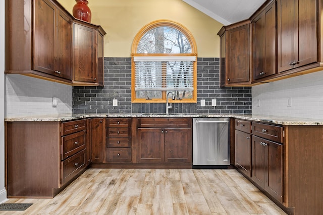 kitchen featuring light wood-type flooring, light stone counters, dark brown cabinetry, and sink