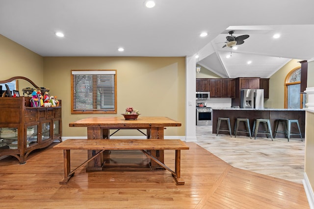 dining room featuring ceiling fan, light wood-type flooring, and vaulted ceiling