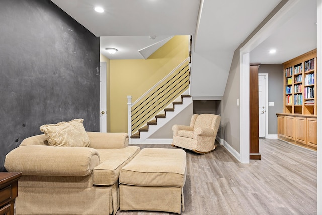 living room with built in shelves and light hardwood / wood-style flooring