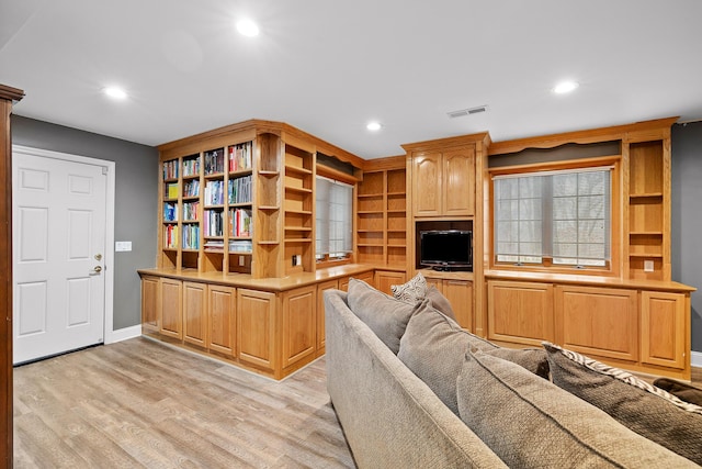 living room featuring built in features and light hardwood / wood-style flooring