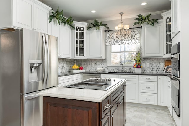 kitchen with stainless steel fridge, crown molding, white cabinetry, and sink