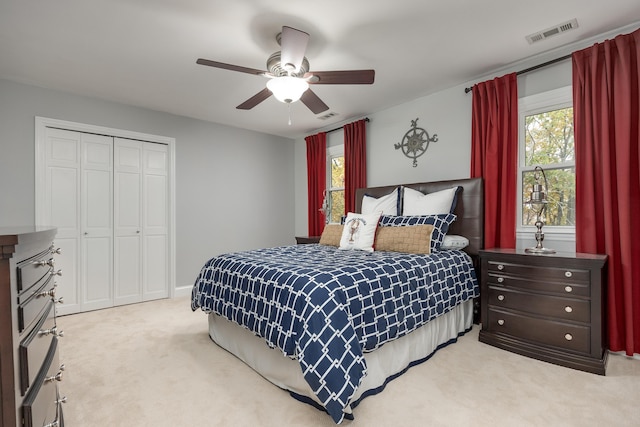 bedroom featuring multiple windows, ceiling fan, a closet, and light carpet