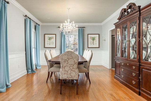 dining space with light hardwood / wood-style floors, crown molding, and a notable chandelier