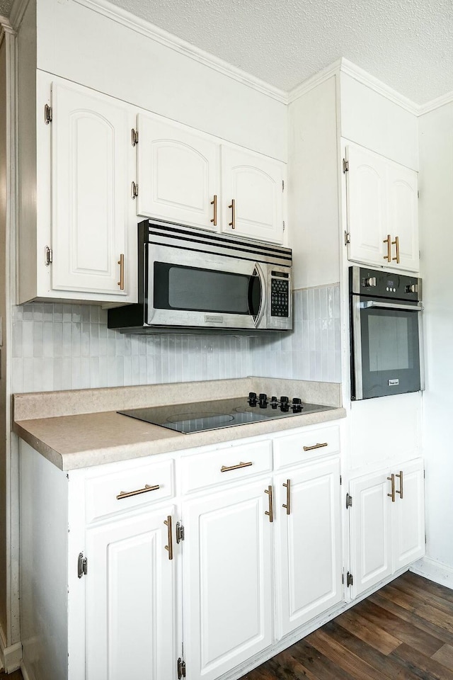 kitchen with white cabinetry, stainless steel appliances, a textured ceiling, decorative backsplash, and dark wood-style floors