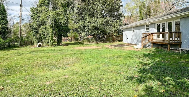 view of yard featuring a deck, fence, and french doors