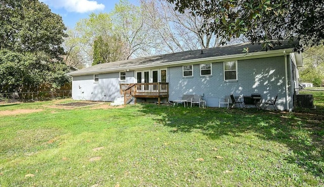 rear view of house featuring fence, french doors, a deck, brick siding, and a yard