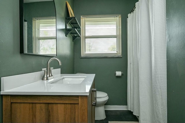 full bath featuring toilet, vanity, and baseboards