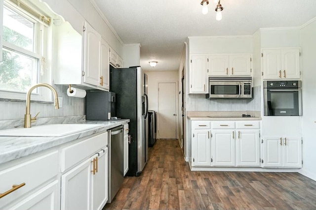 kitchen featuring white cabinets, light countertops, ornamental molding, a sink, and black appliances