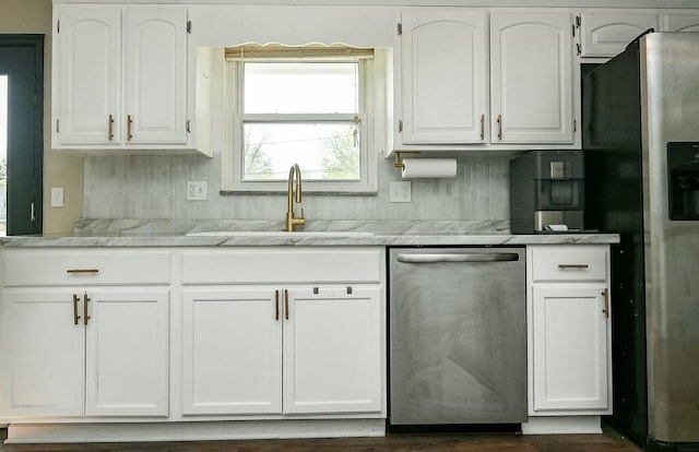kitchen featuring backsplash, a sink, white cabinetry, light stone countertops, and stainless steel appliances