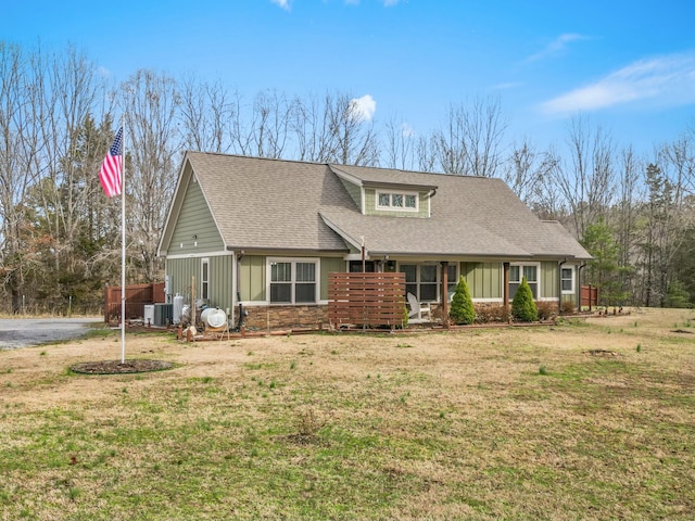 view of front of house with board and batten siding, cooling unit, a shingled roof, and a front lawn